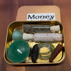 May include: A gold metal tin box with the words "Money Altar Kit" on the lid. The box contains a green candle, a small green stone, a glass vial with dried herbs, a glass vial with white salt, a brown incense cone, a small brown seed pod, and a length of twine.