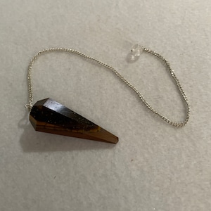 May include: A brown and gold tiger's eye pendulum with a silver chain.