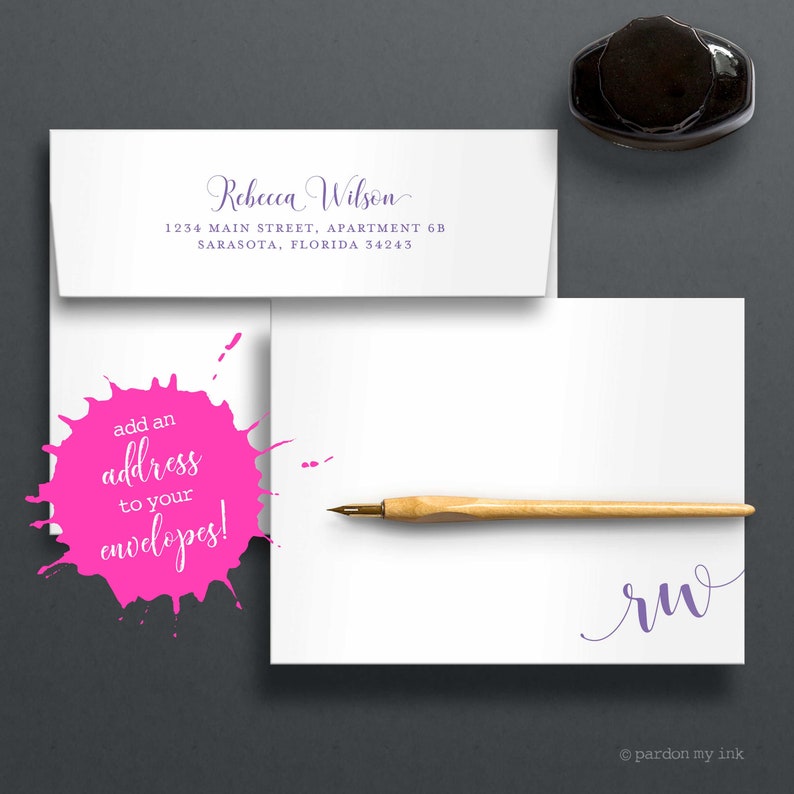 May include: A white envelope with a pink splatter design and the text "add an address to your envelopes!"  The envelope is addressed to Rebecca Wilson at 1234 Main Street, Apartment 6B, Sarasota, Florida 34243.  A wooden calligraphy pen and a black inkwell are also pictured.