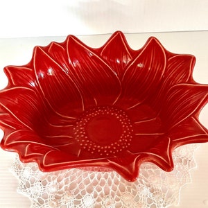 May include: A red ceramic bowl shaped like a sunflower with a raised center and textured petals.