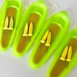 May include: Four bright green corn on the cob serving dishes with yellow corn holders. Each dish has a molded corn design and a small indentation for butter.