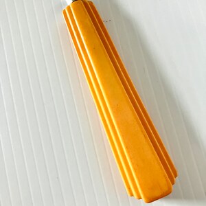 May include: A yellow plastic handle with a silver metal shaft. The handle has a geometric design.