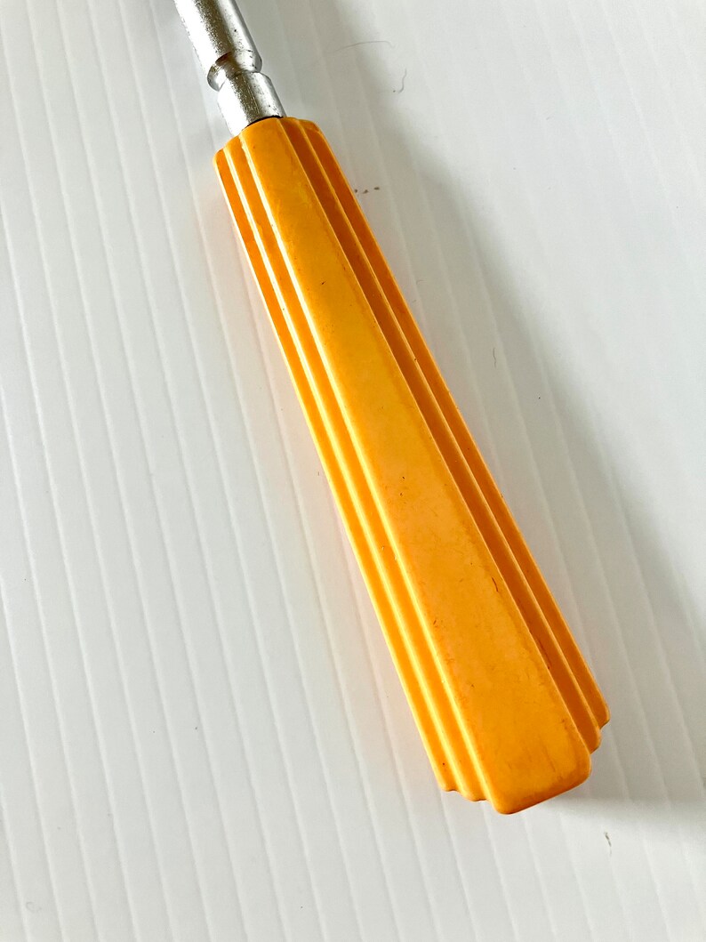 May include: A yellow plastic handle with a silver metal shaft. The handle has a geometric design.
