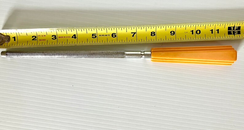 May include: A silver metal knife sharpener with a yellow plastic handle. The sharpener is 11 inches long.