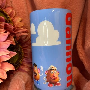 May include: A blue tumbler with a white cloud design and the name "Gannon" in red lettering. The tumbler features a cartoon image of Mr. and Mrs. Potato Head from the Toy Story film.