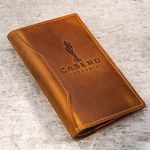 May include: A brown leather menu cover with a cactus and the text "CASERO TAQUERIA" embossed on the front.