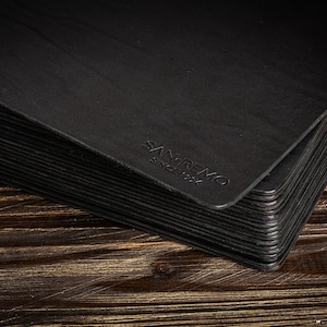 May include: A stack of black leather placemats with the text "Sanremo Since 1984" embossed on the top mat.