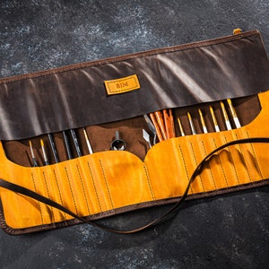 May include: A brown leather roll-up case with a yellow interior and a personalized label that says "BJM". The case is filled with various paintbrushes and tools.
