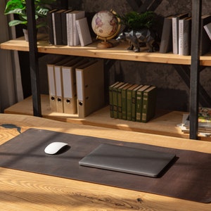 May include: A brown leather desk mat with a white computer mouse and a closed laptop on a wooden desk.