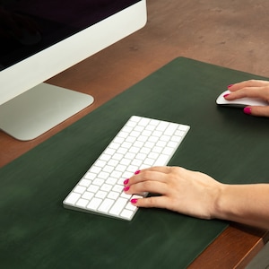 May include: A green leather desk mat with a white wireless keyboard and mouse. The keyboard and mouse are on a green desk mat.