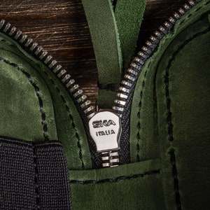 May include: Close-up of a green leather zipper pull with the text "SKA ITALIA" on it.