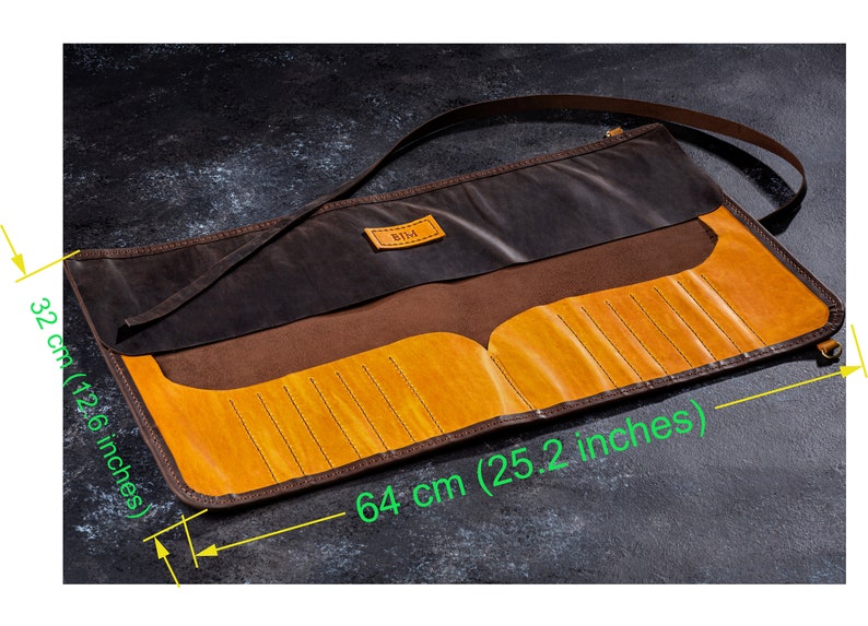 K&ouml;nnte beinhalten: Eine braune Lederrolle mit gelbem Lederinnenfutter und einem Riemen. Die Rolle ist 64 cm lang und 32 cm breit. Sie tr&auml;gt ein Etikett mit der Aufschrift "BIDA".