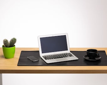 May include: A black leather desk mat with a laptop, a smartphone, and a black coffee cup on a wooden desk.