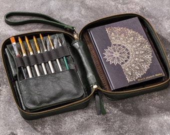 May include: A green leather zippered case with a black sketchbook inside. The sketchbook has a gold mandala design on the cover and the text "Black Sketch Note". The case has a zippered pocket on the front and a strap.