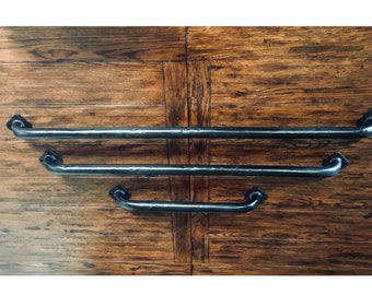 May include: Three dark gray metal grab bars of varying lengths arranged horizontally. Each bar features a smooth, cylindrical rod with a slightly textured finish and a diamond-shaped mounting plate at each end, each containing two screw holes.