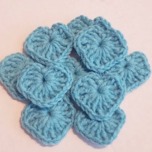 Op de afbeelding: Een groep gehaakte harten in een lichtblauwe kleur. De harten zijn in een cluster gerangschikt, met enkele overlappende.
