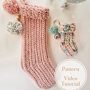 Peut inclure: Une chaussette de Noël en tricot rose avec un pompon blanc sur le dessus. Une plus petite chaussette en tricot multicolore avec un pompon vert est également représentée. Le texte "Pattern + Video Tutorial" est sur un cercle blanc avec un contour doré.