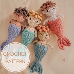 May include: Four crocheted mermaid dolls in different colors. The dolls have yarn hair and are wearing crocheted tails. The tails are in shades of blue, green, pink, and peach. The dolls are arranged on a wooden surface. The text "CROCHET PATTERN" is visible in the image.