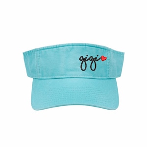 May include: A light blue visor with the word "gigi" embroidered in black script with a red heart next to it.