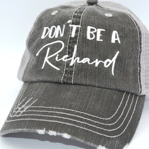 May include: A gray and white baseball cap with the text "Don't be a Richard" embroidered in white on the front.