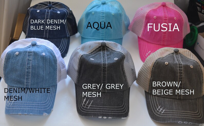 May include: Six different colored baseball caps with mesh backs. The caps are in the following colors: dark denim with blue mesh, aqua, fuchsia, denim with white mesh, grey with grey mesh, and brown with beige mesh.