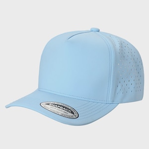 May include: A light blue five-panel snapback cap with laser-cut ventilation holes on the side panels. The brim features a circular sticker with the text: LEADING THE WAY IN MODERN HEADWEAR SNAPBACK DO IT YOUR WAY FINEST QUALITY HEADWEAR.