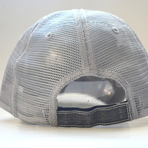 May include: A gray mesh trucker hat with a black adjustable strap in the back.