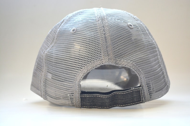 May include: A gray mesh trucker hat with a black adjustable strap in the back.