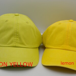 May include: Two baseball caps, one neon yellow and one lemon yellow. The neon yellow cap has the text "NEON YELLOW" below it. The lemon yellow cap has the text "lemon YELLOW" below it.