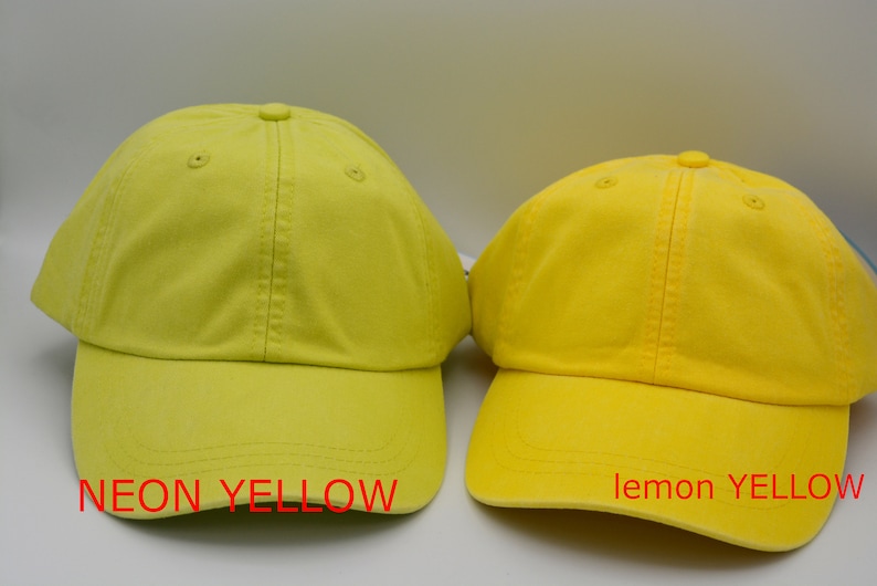 May include: Two baseball caps, one neon yellow and one lemon yellow. The neon yellow cap has the text "NEON YELLOW" below it. The lemon yellow cap has the text "lemon YELLOW" below it.