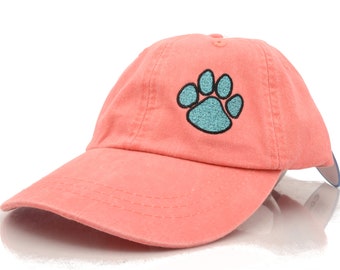May include: A coral pink baseball cap with a light blue paw print embroidered on the front.