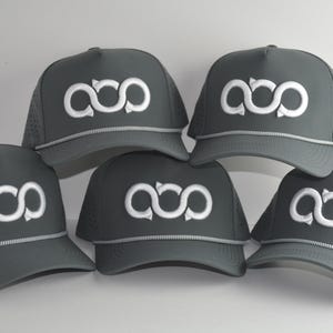 May include: Five dark grey baseball caps arranged in a group. Each cap features a white embroidered infinity-style logo on the front panel, a light grey rope detail across the base of the crown, and perforated side panels for ventilation.