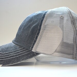 May include: A black and gray distressed trucker hat with a mesh back.
