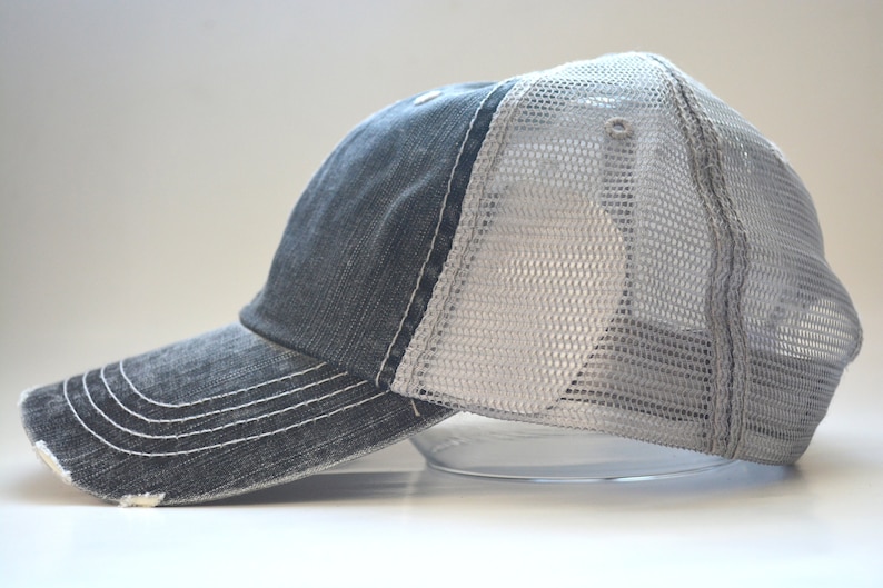 May include: A black and gray distressed trucker hat with a mesh back.