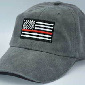 May include: A gray baseball cap with a red line American flag patch. The flag is embroidered with white stars and red and white stripes.
