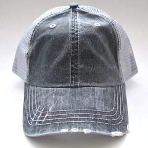 May include: A gray and white distressed trucker hat with a mesh back.