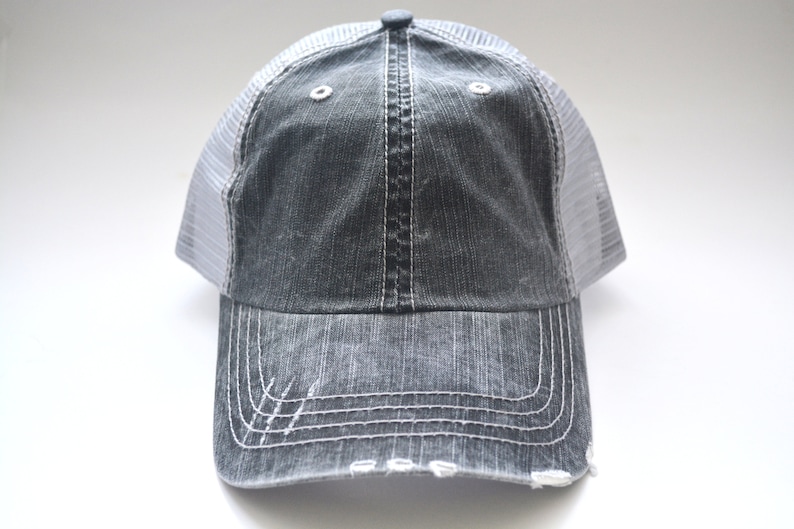 May include: A gray and white distressed trucker hat with a mesh back.