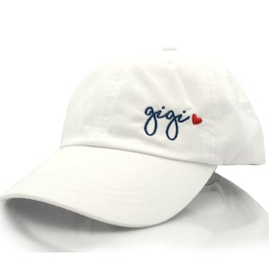 May include: White baseball cap with a navy blue embroidered cursive word "gigi" and a small red heart.
