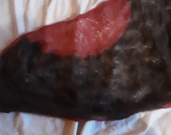 May include: A red and black knitted scarf with a lacy pattern. The scarf is folded in half and lying on a white surface.