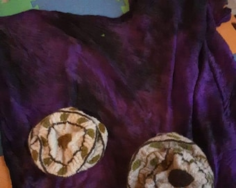 May include: Two knitted hats with a brown and green pattern on a purple background.