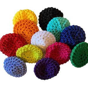 May include: A collection of colorful, crocheted scrubbies in various shades, including yellow, orange, red, white, green, blue, purple, and black. These handmade items are round and textured, perfect for kitchen or bath use.
