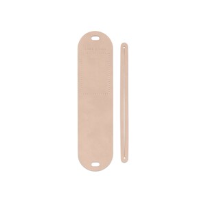 May include: A light pink leather luggage tag with a small pocket and a long strap. The tag has the text "Lark & Ives" printed on it.