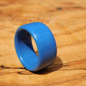 May include: A bright blue ring made of resin. The ring is smooth and has a glossy finish.
