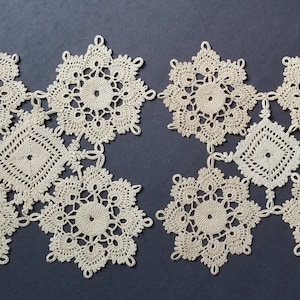 May include: Six delicate crocheted doilies in a cream color, arranged in a symmetrical pattern on a dark blue background.