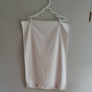 Puede incluir: Mantel de mesa de algod&oacute;n blanco con borde festoneado y flores bordadas en tonos rosa y blanco.