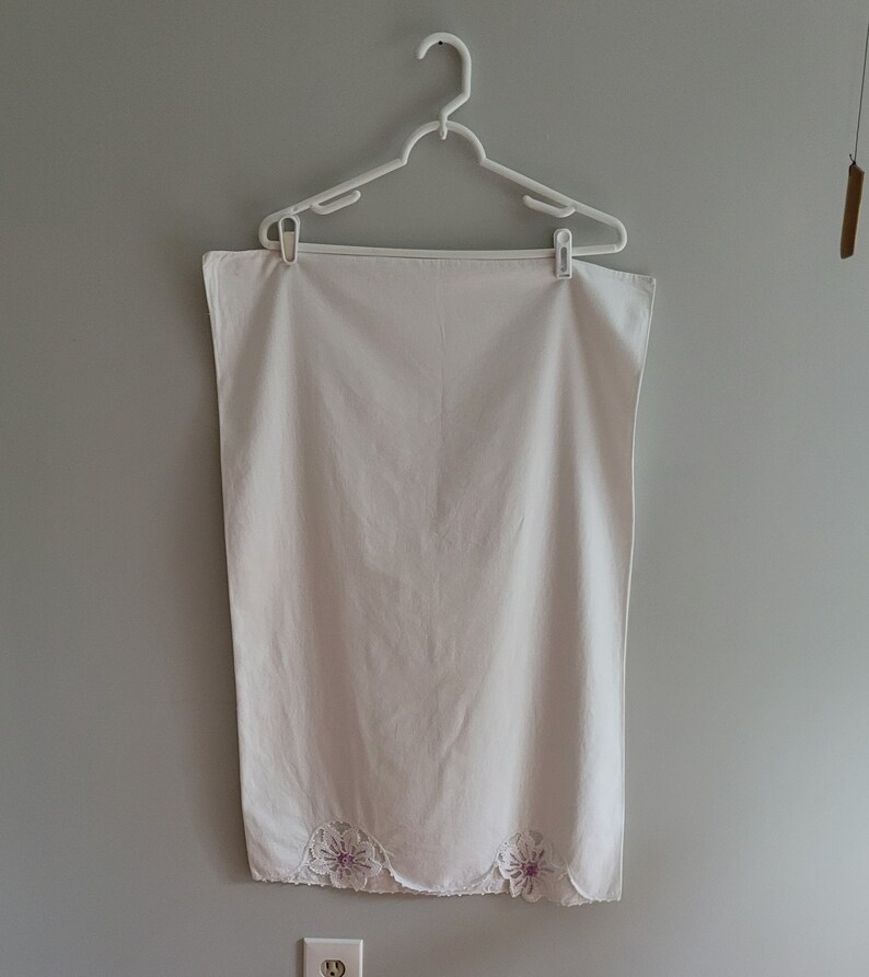 Puede incluir: Mantel de mesa de algod&oacute;n blanco con borde festoneado y flores bordadas en tonos rosa y blanco.