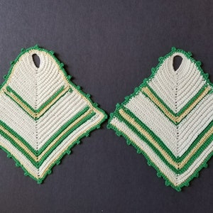 May include: Two white crocheted pot holders with green and yellow stripes. The pot holders have a diamond shape with a hole in the center.