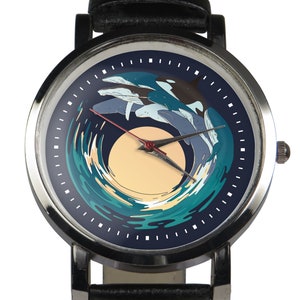 Könnte beinhalten: Eine Armbanduhr aus schwarzem Leder mit einem silbernen Gehäuse und einem blauen Zifferblatt. Das Zifferblatt zeigt eine Grafik von Delfinen, die durch eine Welle springen, mit einer gelben Sonne im Hintergrund.