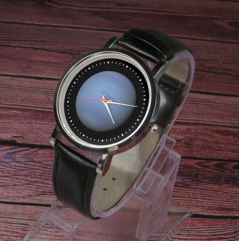 May include: A silver wristwatch with a black leather strap. The watch face has a black background with a blue and white circular design.