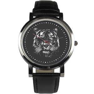 May include: A black leather wristwatch with a silver face and a white tiger illustration. The tiger has a red eye patch.